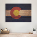 Wooden wall art with Colorado flag design on a white wall above a wooden shelf.